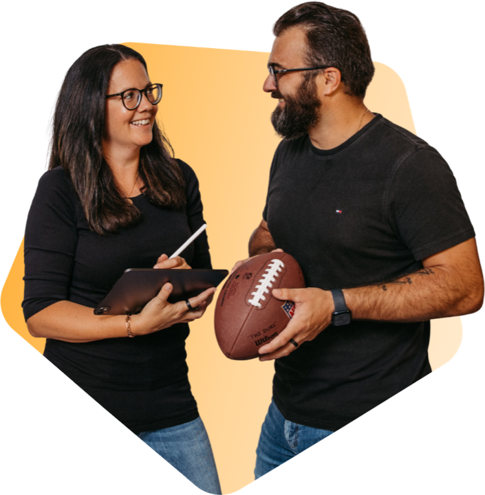 Romana und Florian Hieß im Gespräch, sie notiert auf einem Tablet, er hält einen Football